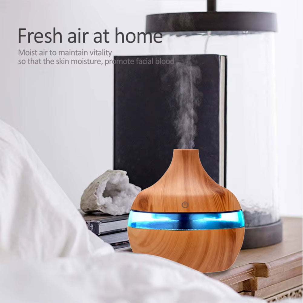 Portable USB mini air humidifier releasing mist with wooden finish and blue LED light on bedside table
