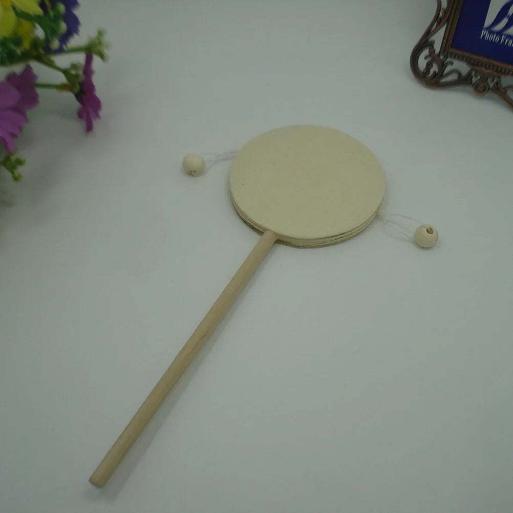 DIY rattle-drum wooden toy with handle, surrounded by flowers.