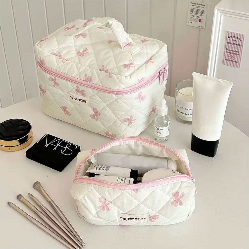 Quilted floral cotton makeup bag with bow accent, spacious interior, and secure zipper closure.