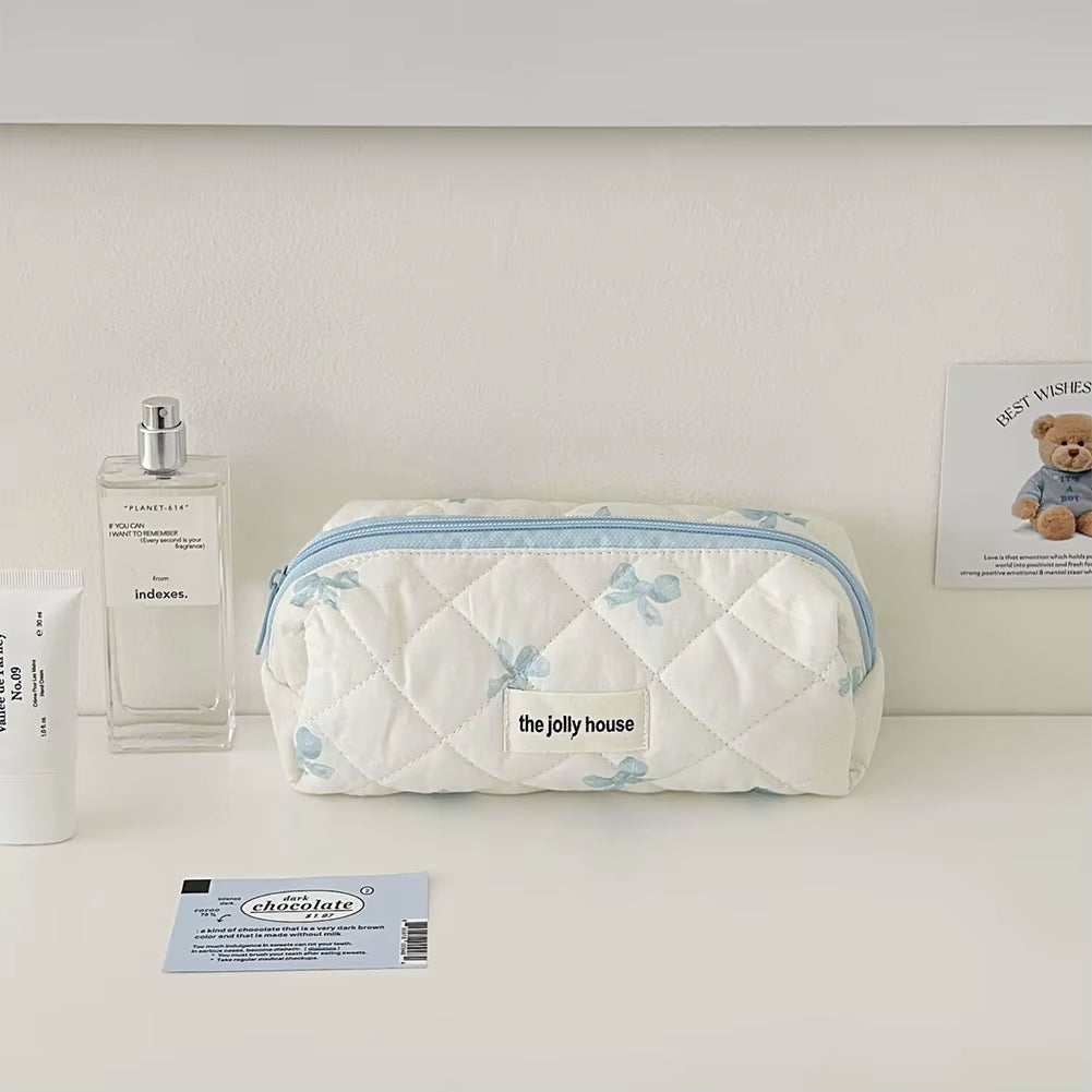 Quilted cotton floral makeup bag with bow accent, spacious interior, and secure zipper closure, ideal for travel.
