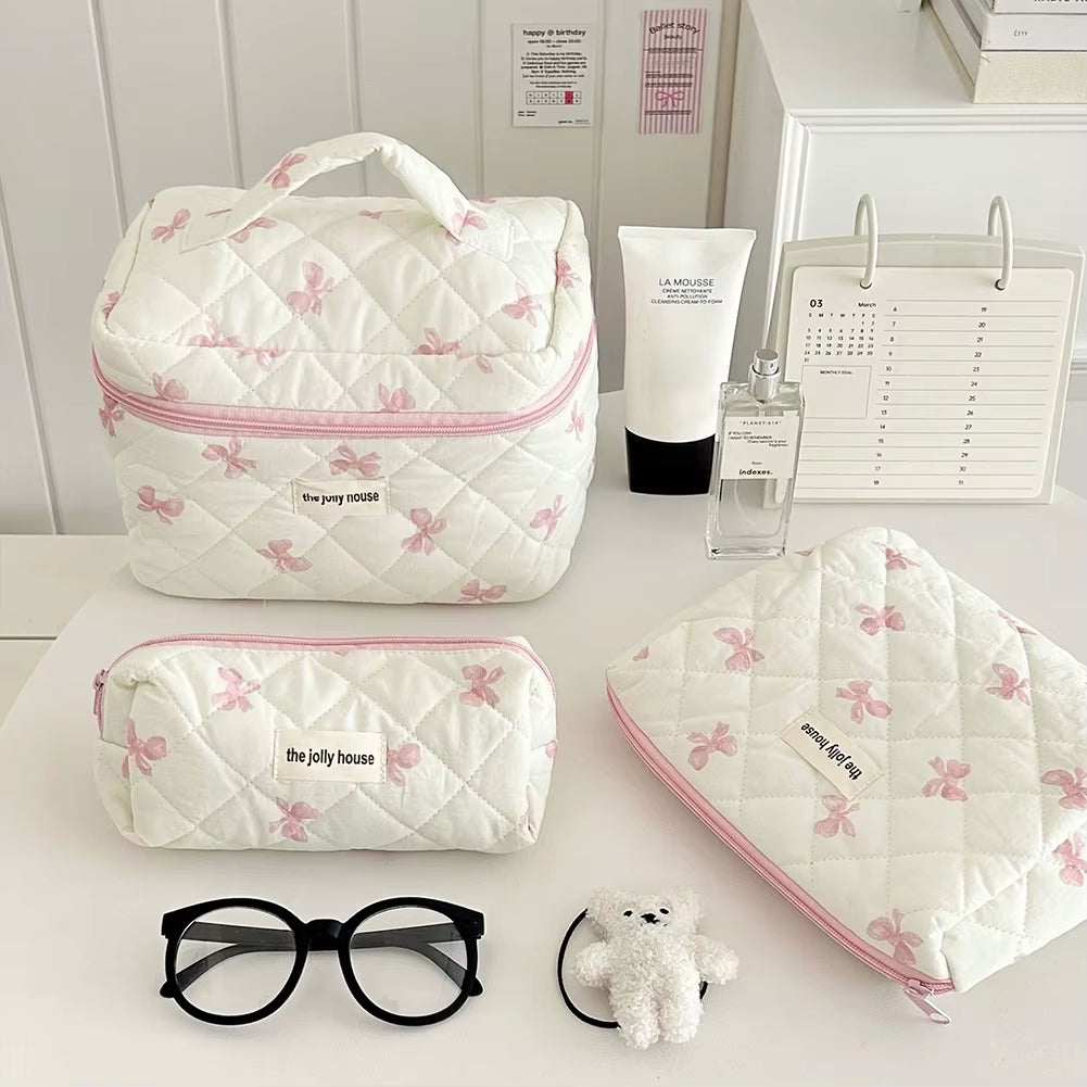 Quilted floral makeup bag with bow accent, portable and spacious for cosmetics storage.
