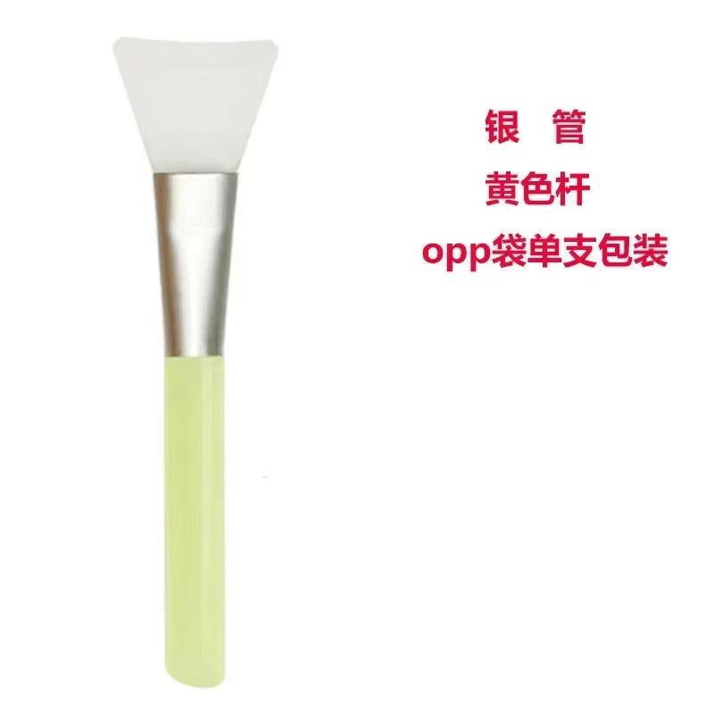 Silicone Facial Mask Brush with flexible head and yellow handle.