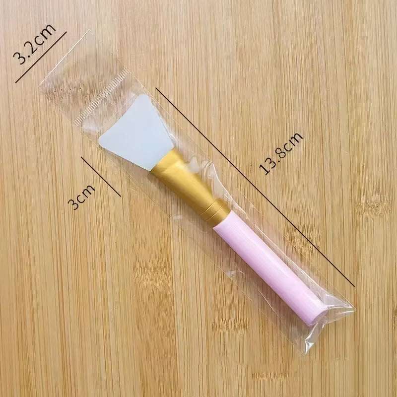Silicone facial mask brush with soft pink handle, high-quality silicone head, in protective packaging.