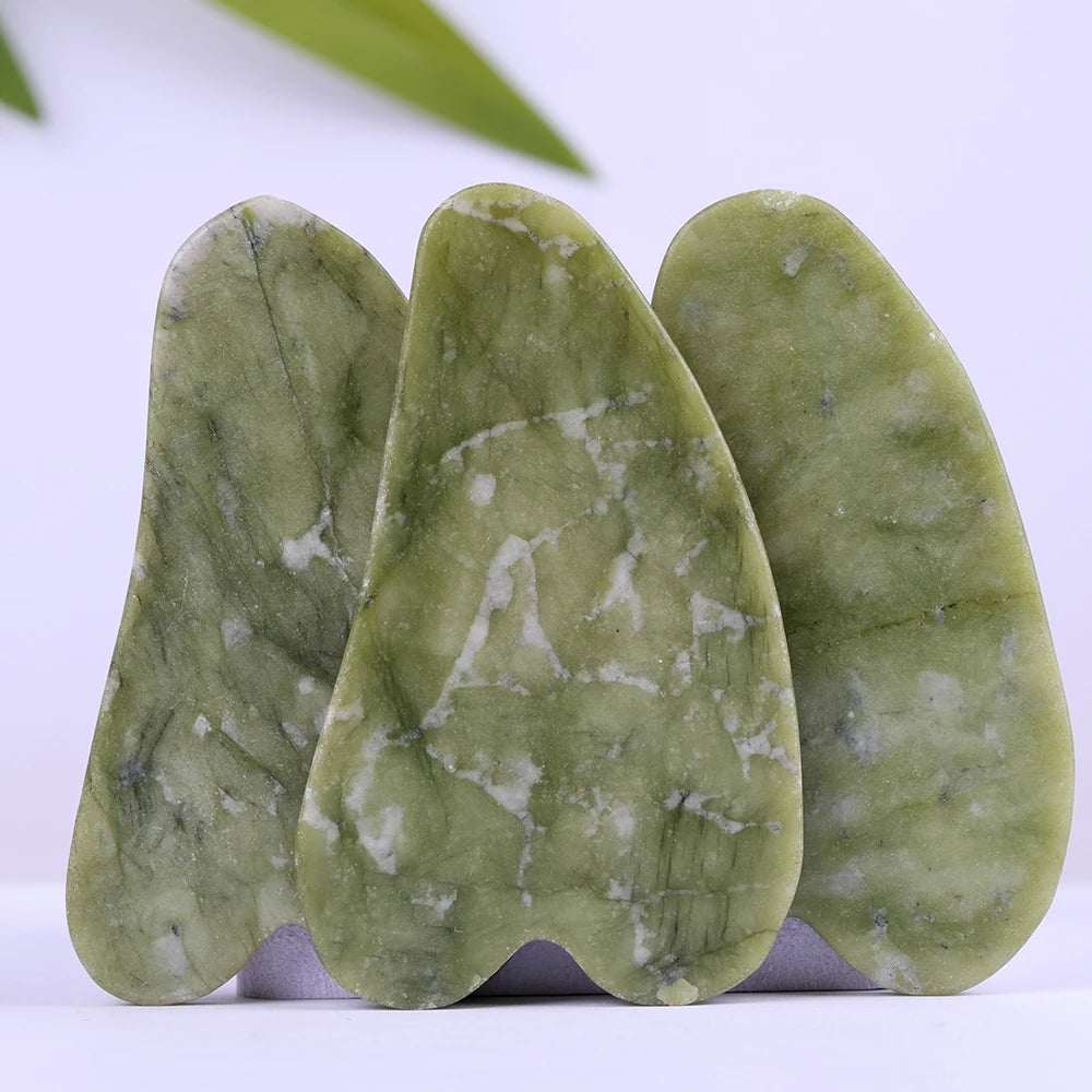 Natural jade Gua Sha scrapers displayed on a white surface, ideal for face roller skincare therapy.