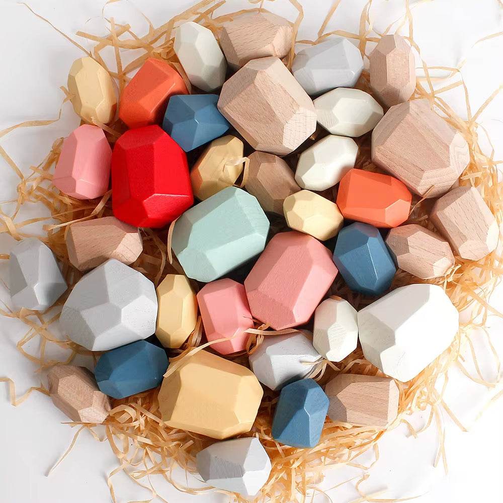 Colorful wooden sensory stacking stones for toddlers on wood shavings.