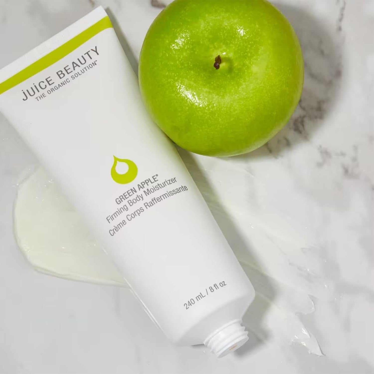 Green Apple Firming Body Moisturizer tube with green apple on marble surface