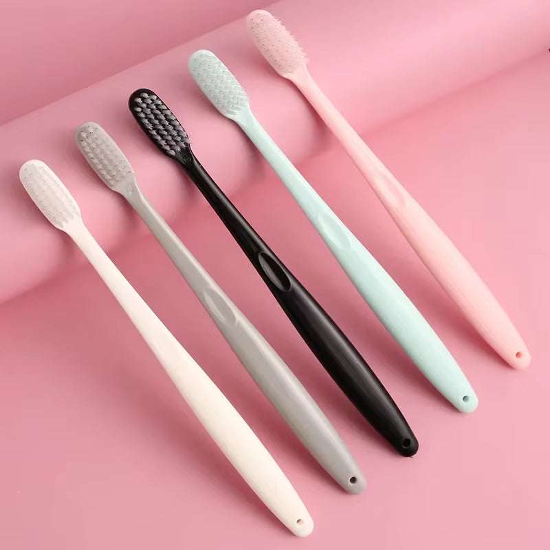 Eco-friendly bamboo charcoal toothbrush set with natural bamboo handles and black bristles on a pink background.
