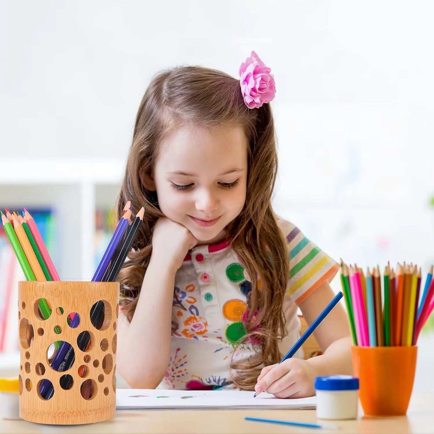 Bamboo organizer holding colored pencils on a desk next to a young girl drawing