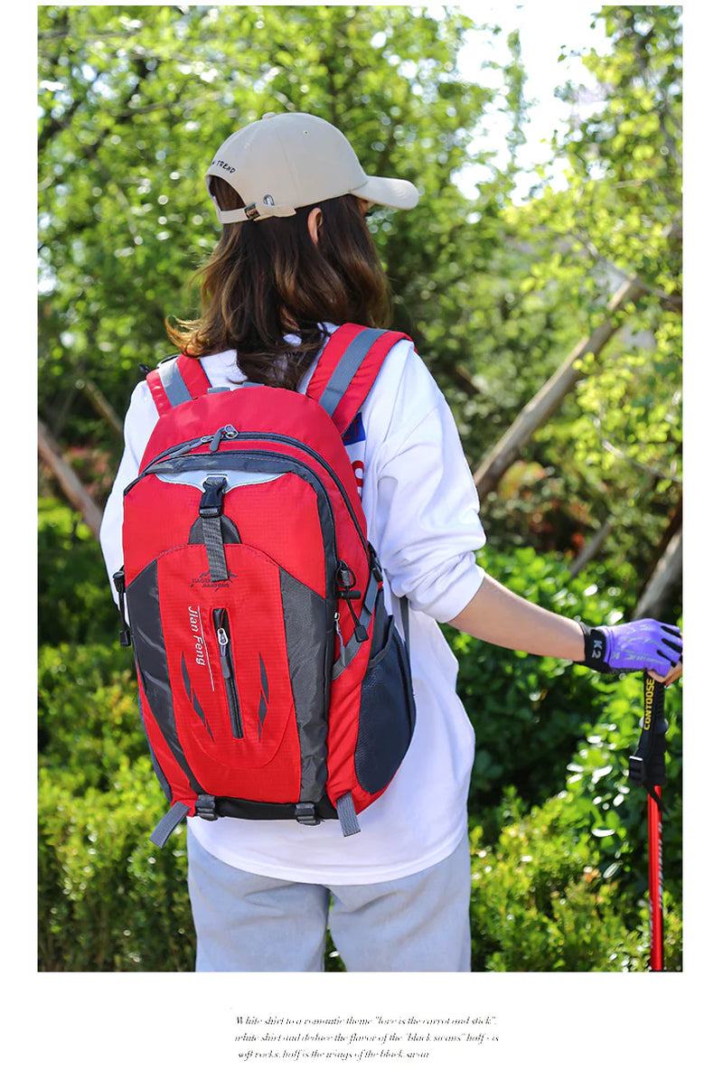Red rucksack laptop travel backpack worn by a hiker in a forest setting.