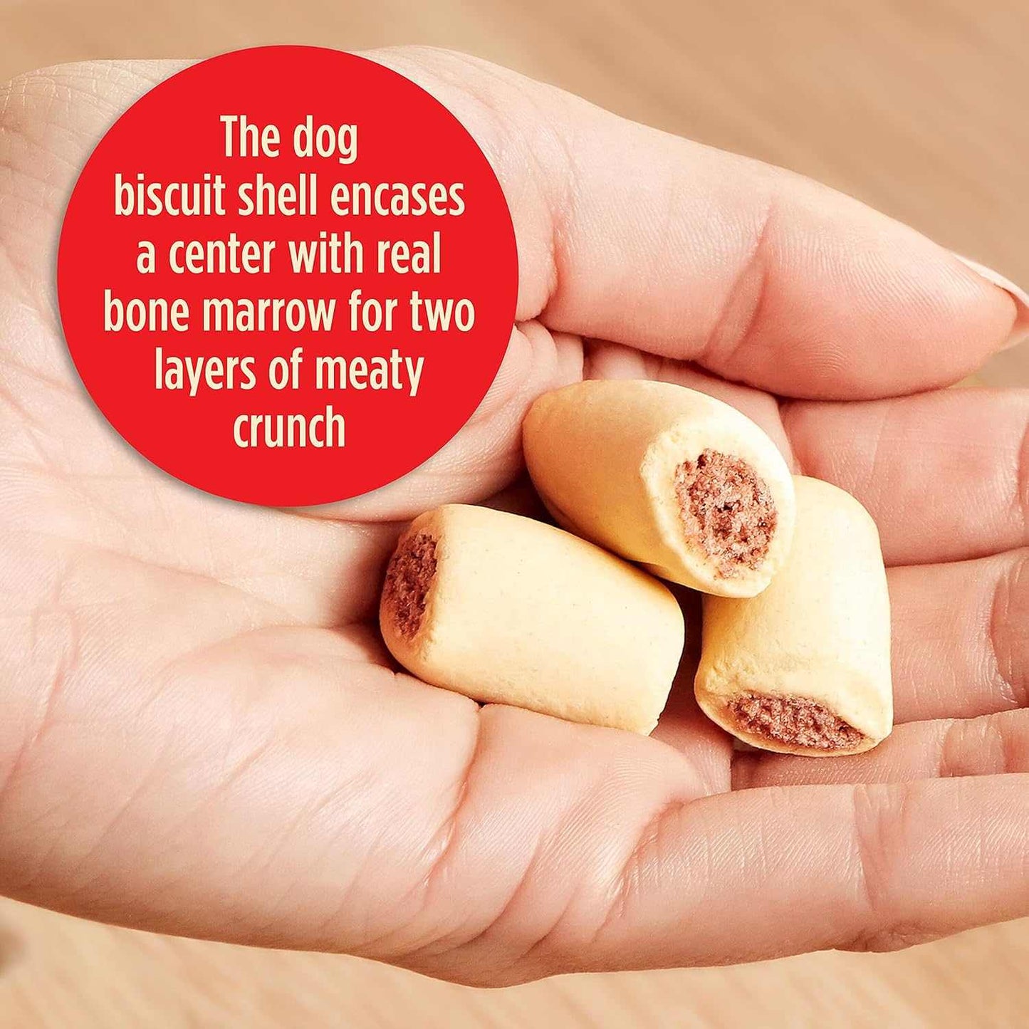 Hand holding small dog treats with bone marrow center, two layers of meaty crunch, high-protein dog biscuits for dental health and training