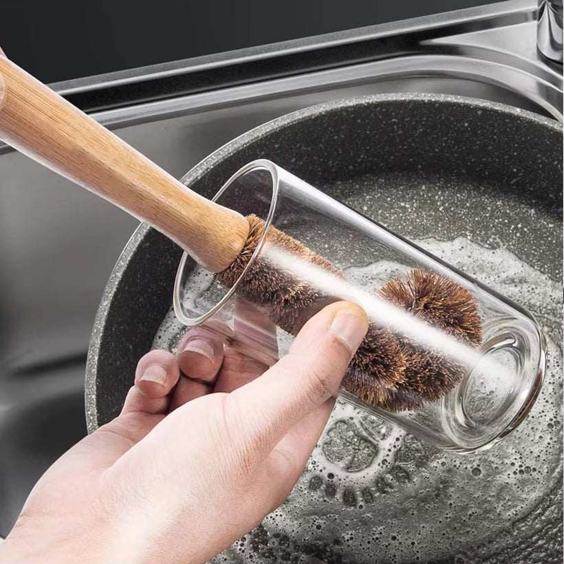 Eco-friendly bamboo cleaning brush set with natural bamboo handle and plant-based bristles cleaning a glass.