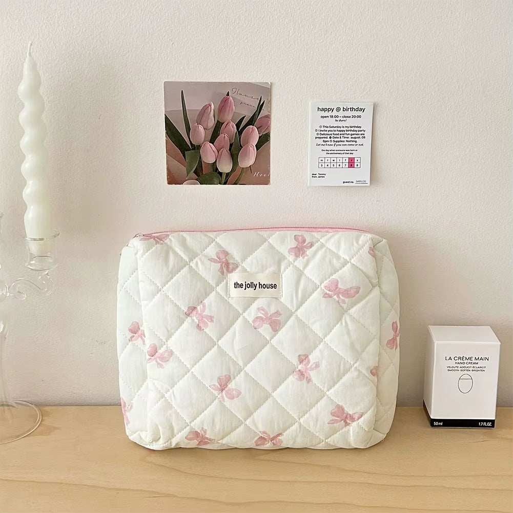Quilted cotton makeup bag with floral pattern and bow accents, featuring a secure zipper closure.