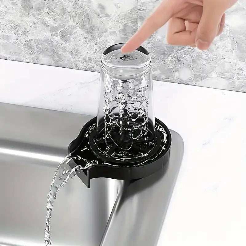High pressure automatic cup washer in use, mounted on a kitchen sink, cleaning a glass with water jets.