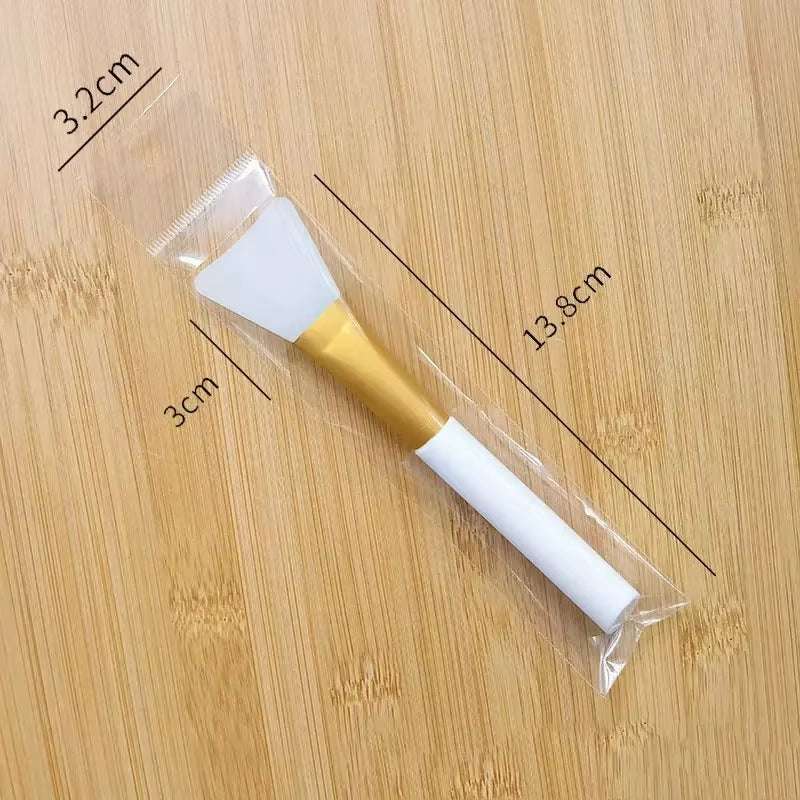 Silicone facial mask brush with soft applicator head on a wooden surface, measuring 13.8 cm in length.
