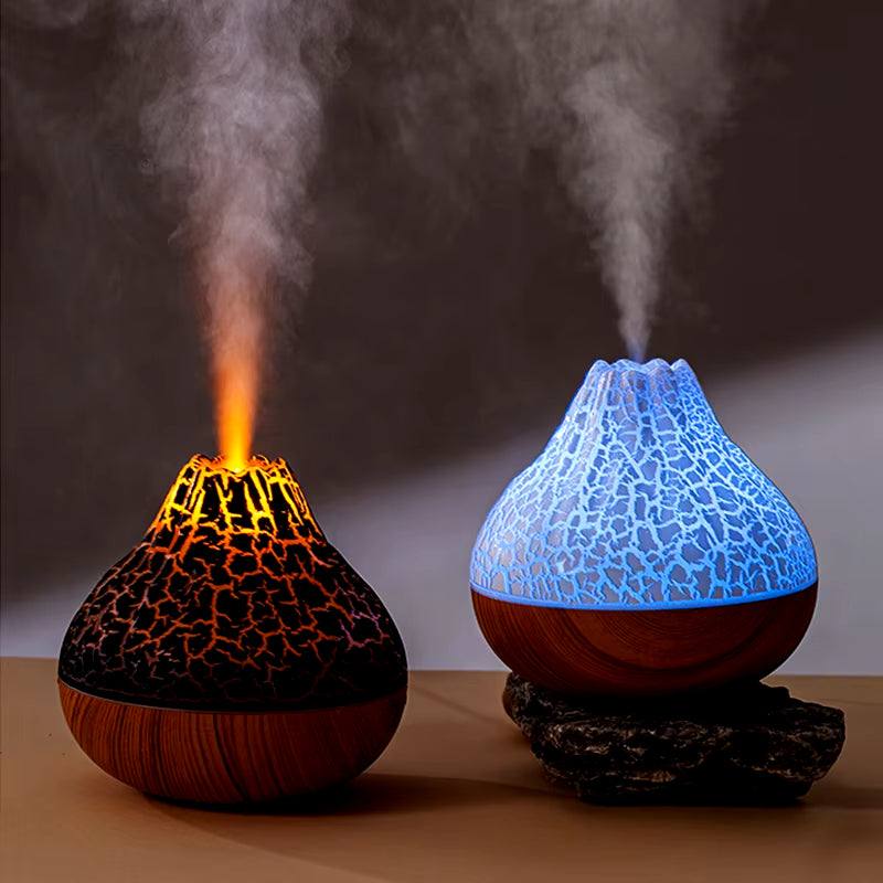 Two desktop electric USB air humidifiers shaped like volcanoes emitting mist with one glowing orange and the other blue with a cracked surface design