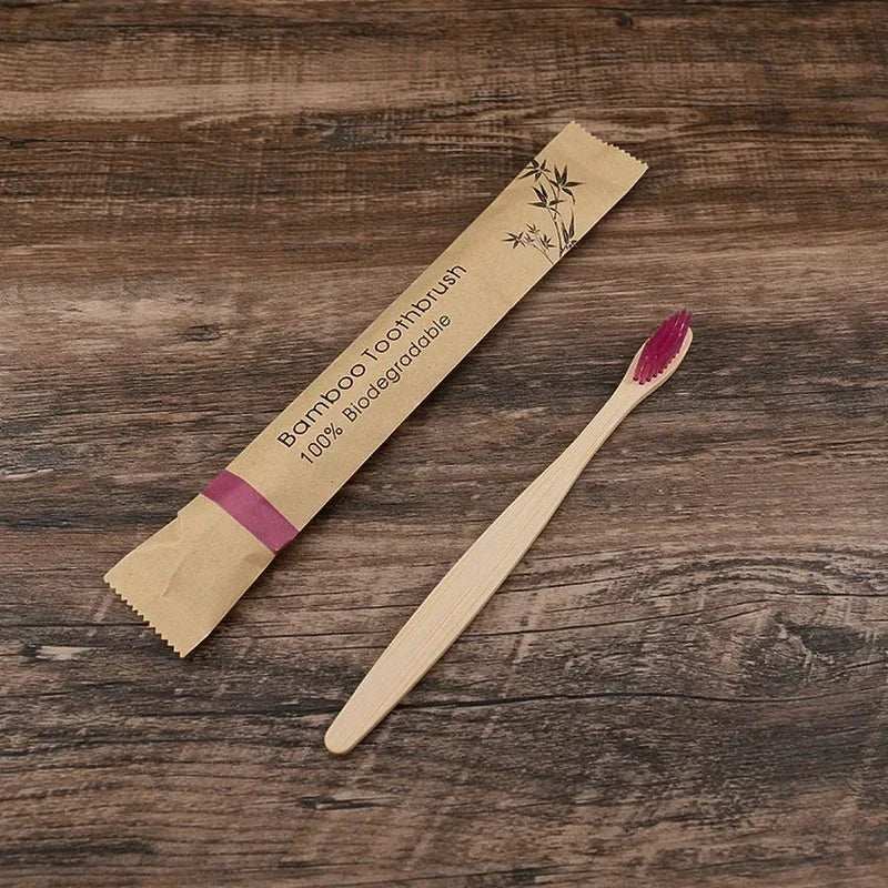 Natural bamboo toothbrush with soft pink charcoal-infused bristles, eco-friendly and biodegradable packaging