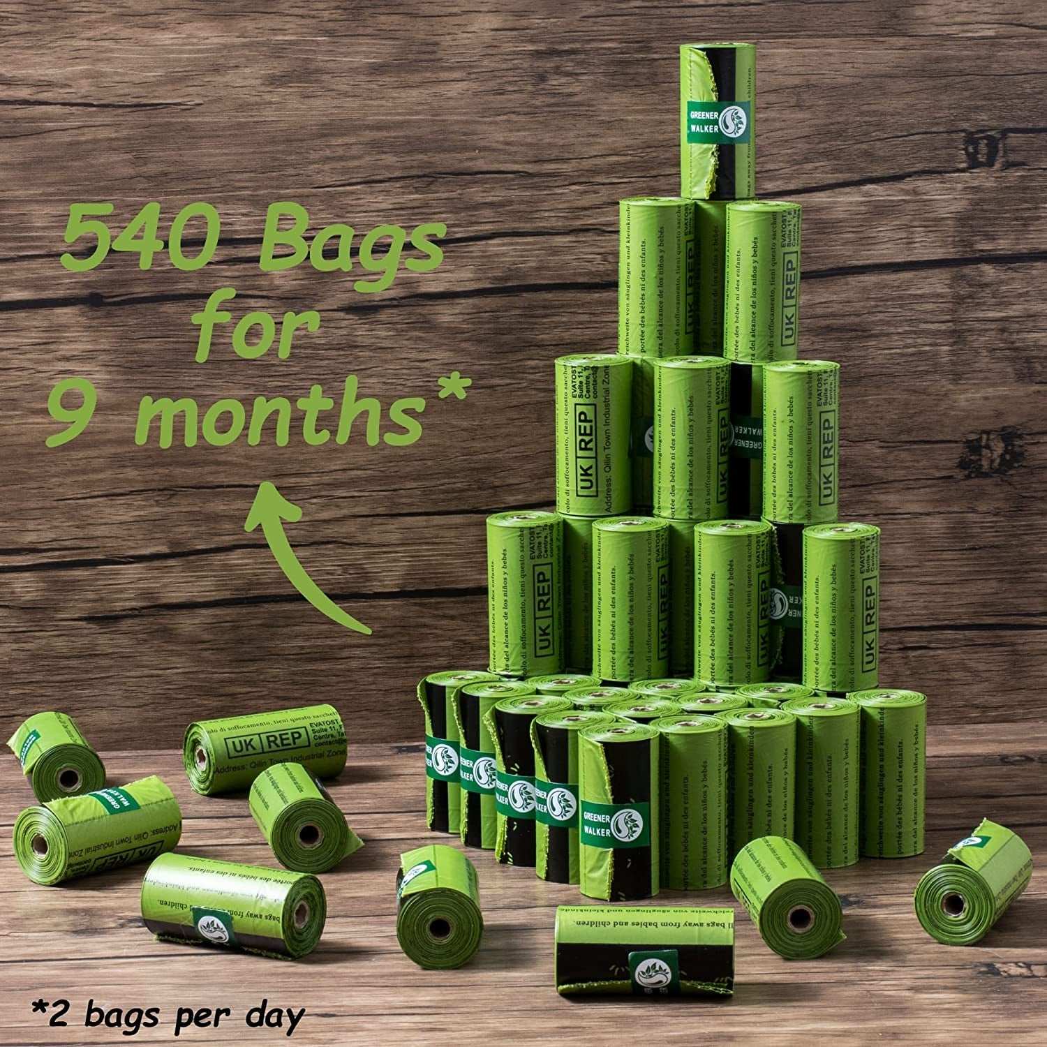 Green rolls of poop bags for dog waste stacked in a pyramid on a wooden surface with text indicating 540 bags for 9 months use