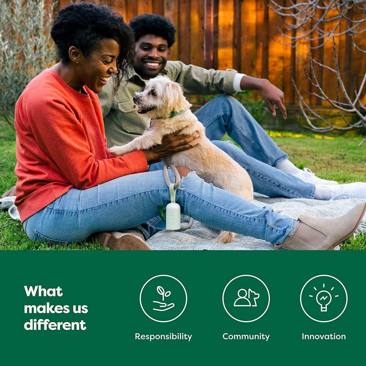 Happy couple sitting outside with their dog and a green dog poop bag holder attached to the leash on grass