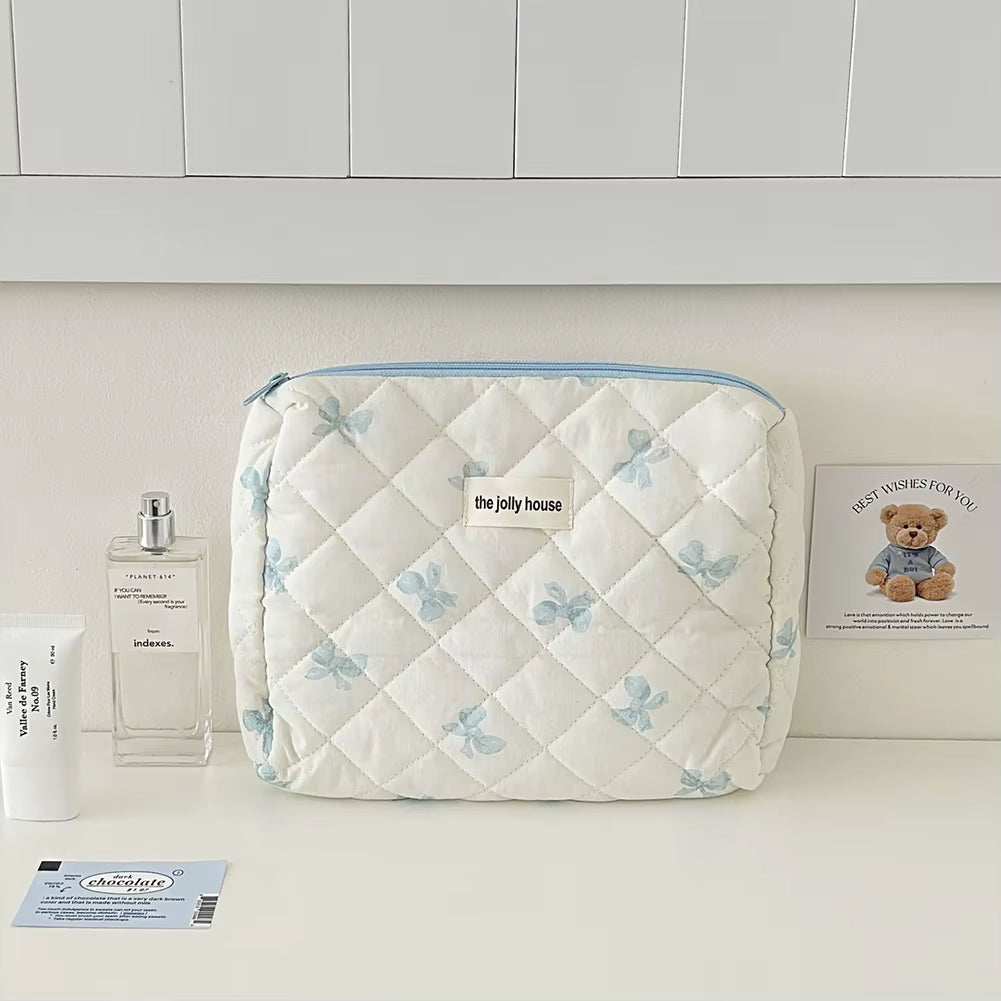 Quilted cotton floral makeup bag with bow accent, ideal for cosmetics storage and travel.