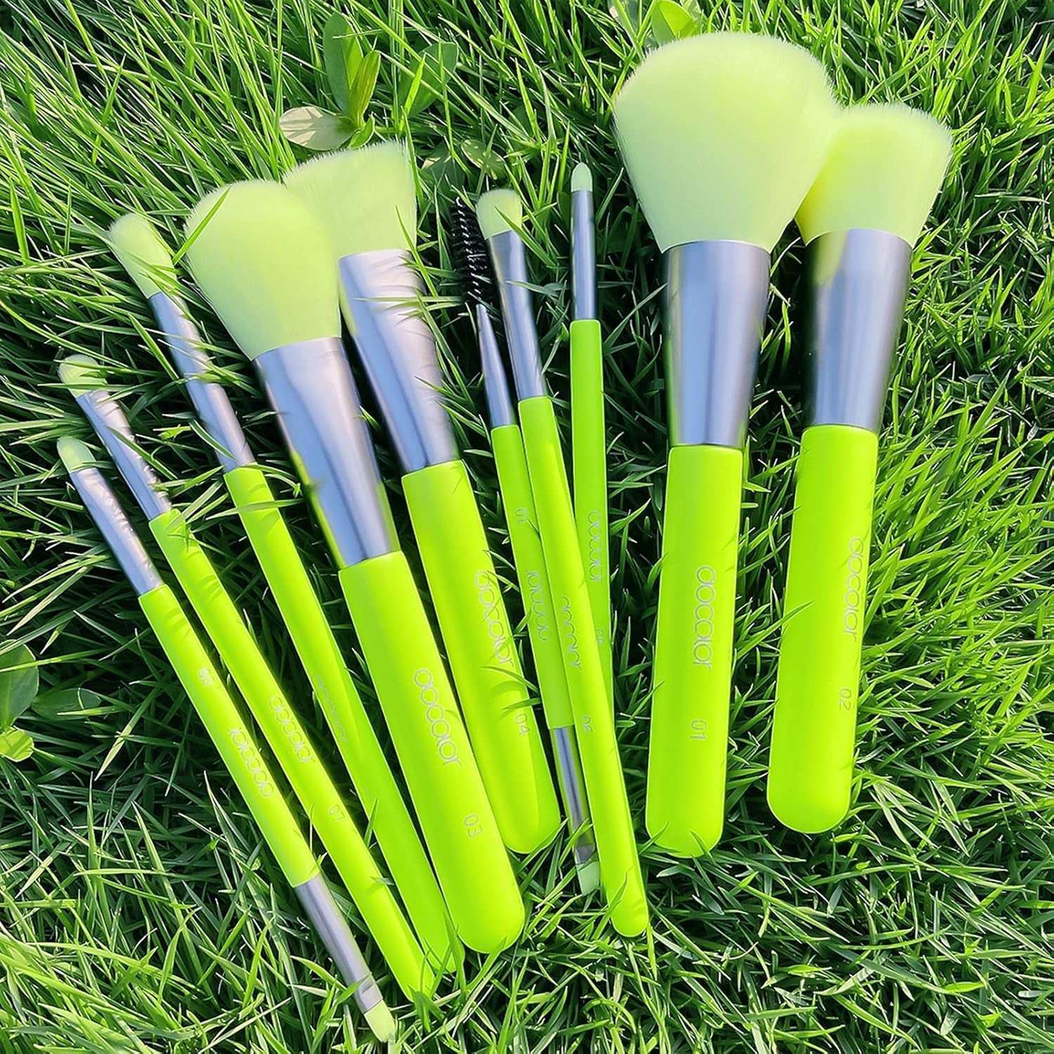 Neon green makeup brush and sponge set on grass, featuring 10 brushes and 3 pea pod sponges for vibrant looks.
