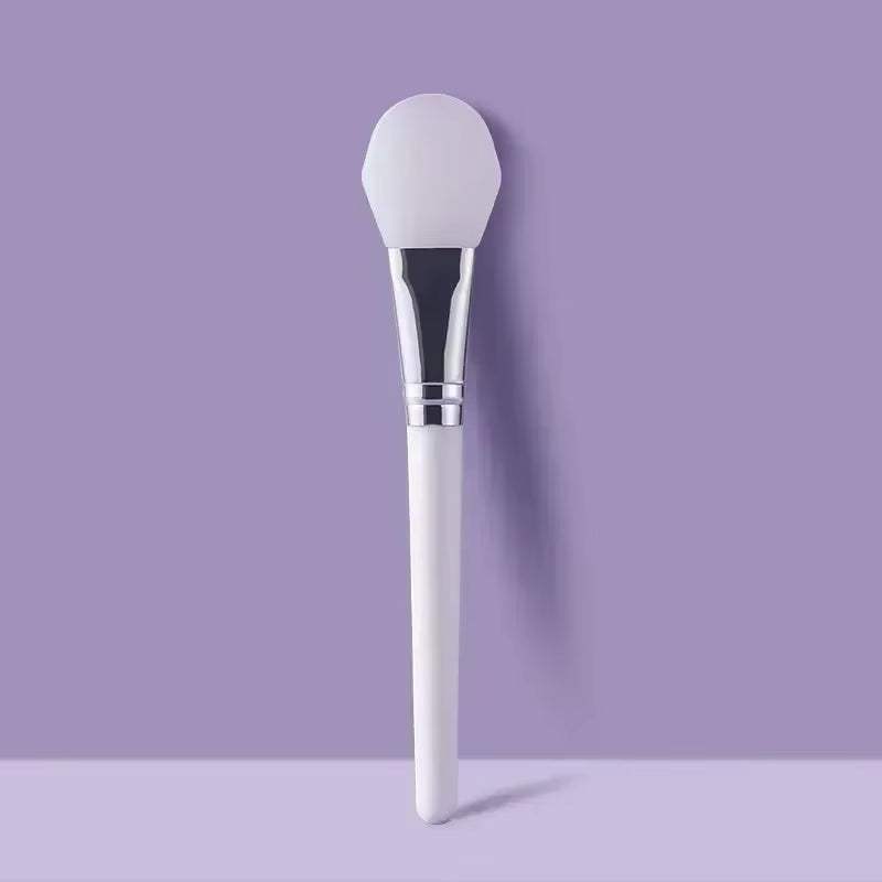 Silicone facial mask brush with a soft silicone head and durable handle on a purple background, ideal for applying skincare products.